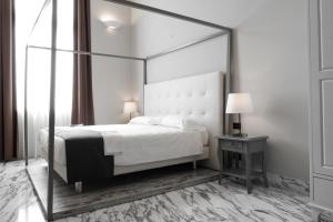 Hotel De Ville في جينوا: غرفة نوم بسرير مظلة وطاولة مع مصباح