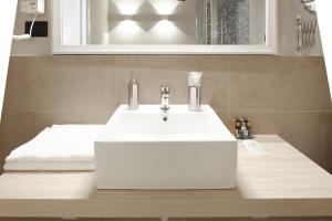 bagno con lavandino bianco e specchio di Hotel De Ville a Genova