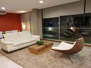 sala de estar con sofá blanco y silla en Apart Altos del Virrey, en Colonia del Sacramento
