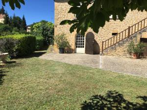 a brick building with a door and a grass yard at Gite à Sarlat avec piscine in Sarlat-la-Canéda