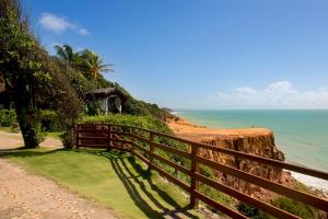 a fence on the side of a cliff near the ocean at Hotel Ponta do Madeiro in Pipa