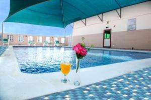a vase of flowers and a glass of orange juice next to a pool at Marco Polo Hotel in Manama