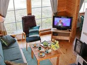 a living room with a couch and a tv at Holiday Home Joutsenlahti by Interhome in Pätiälä