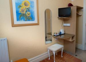 a room with a desk and a mirror and a tv at Somerset House B&B in Grange Over Sands