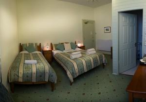 a hotel room with two beds and a desk at Somerset House B&B in Grange Over Sands