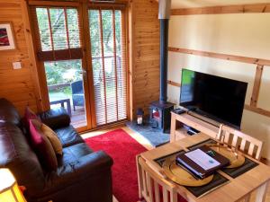 a living room with a couch and a television at Rashfield Sheilings - Riverside Lodges, by Pucks Glen, Dunoon in Dunoon