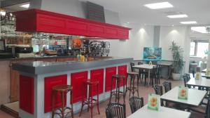 a restaurant with red cabinets and tables and chairs at Hôtel Des Vosges in Contrexéville