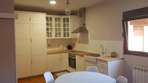 a kitchen with white cabinets and white appliances at La Casina del Cerecedo in León