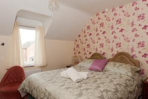 a bedroom with a bed with a flowery wallpaper at Birtley House Guest House B&B in Telford