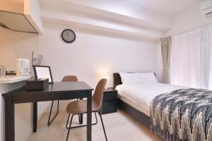 a hotel room with a bed and a desk and a clock at European House Reisen in Fukuoka