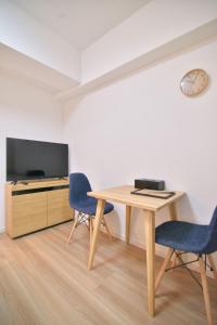 a room with a table and two chairs and a tv at European House Reisen in Fukuoka