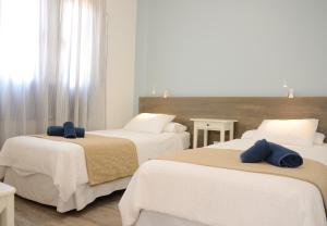 1 Schlafzimmer mit 3 Betten mit weißer Bettwäsche und blauen Kissen in der Unterkunft Apartamentos El Marinero - Caletilla in Caleta de Sebo