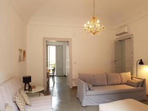 un soggiorno con divano bianco e lampadario pendente di Casa Romeo ad Acireale