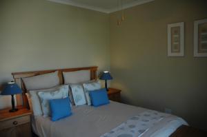 a bedroom with a large bed with blue pillows at Ramsgate Palms D in Ramsgate