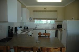 a kitchen with a refrigerator and a table with chairs at Ramsgate Palms D in Ramsgate
