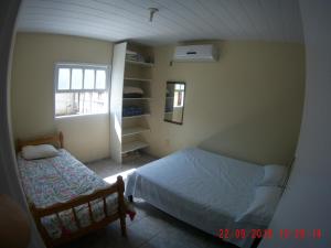 a small bedroom with a bed and a window at Casa na Praia da Pinheira in Palhoça
