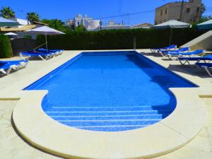 a swimming pool with blue chairs and umbrellas at Apartaments Marina Sol i Pins in Cala Figuera