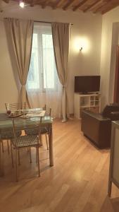 een woonkamer met een tafel en stoelen en een televisie bij Appartamento La Maddalene in Pisa