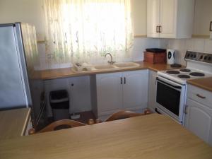 a kitchen with white cabinets and a sink and a stove at Ramsgate Palms J in Ramsgate