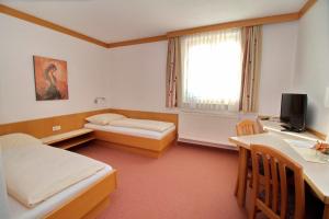 a room with two beds and a desk and a television at Gasthof Huber in Wels