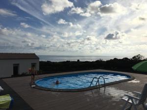 a woman standing next to a swimming pool with the ocean at Insula Vinus Apartments in Madalena
