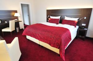 a hotel room with a large bed with a red blanket at Hotel Rheingarten in Duisburg