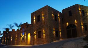 un grand bâtiment en briques avec des lumières sur lui dans l'établissement Palazzo Loupassi Boutique Villas, à Vasilópoulon