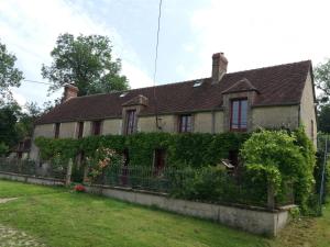 Ein altes Haus mit Efeu nebenbei in der Unterkunft La Berlandière in Le Merlerault