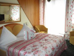 a bedroom with a bed with a floral bedspread and a window at Hotel Winzerverein in Zeltingen-Rachtig