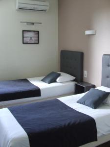 a hotel room with two beds with blue and white sheets at Le Sarac Hôtel in Clermont-lʼHérault +12 photos
