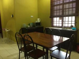 een eetkamer met een houten tafel en stoelen bij Harmony Guesthouse Sdn Bhd in Kampung Padang Masirat