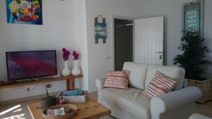 a living room with a white couch and a tv at cansantidesmonestir in La Mola