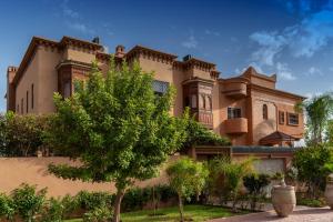 een groot huis met een boom ervoor bij Hôtel Riad Airport Marrakech in Marrakesh