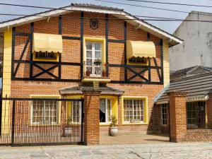 a red brick house with a black gate at Hotel Sans Souci in Belén de Escobar