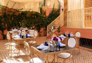 a dining room with tables and chairs and plants at Hôtel Riad Airport Marrakech in Marrakech