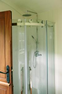 a shower in a bathroom with a glass door at The Huts in the Hills in Llanigon