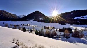 a snow covered mountain with the sun in the sky at Aparthotel Garni Monte in Kartitsch