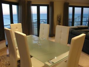 a dining room with a glass table and white chairs at Design Apartments in Ericeira