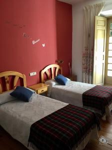 two beds in a room with red walls at Casa Tere in Sigüenza