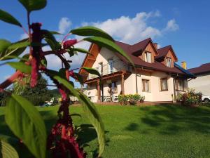 a large house on a lawn with flowers in front of it at Noclegi u Agatki in Ustrzyki Dolne