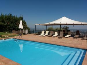 una piscina con sillas y una sombrilla blanca en Can Serrallonga, en Camós