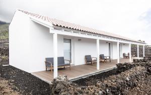 ein weißes Haus mit Stühlen auf einer Holzterrasse in der Unterkunft Insula Atlantis Apartments in Madalena