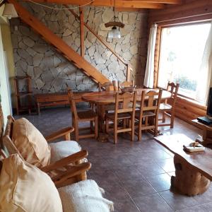 uma sala de jantar com uma mesa de madeira e cadeiras em Cabañas Bahia Radal em Villa Pehuenia