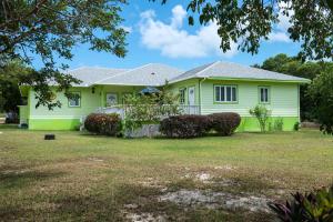 una casa verde con arbustos en el patio en Sir Charles Guest House, en South Palmetto Point