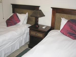 een slaapkamer met 2 bedden en een nachtkastje met een lamp bij Santorini E in Margate