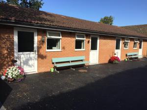 un edificio in mattoni con due panchine di fronte di Linden Tree Holiday Apartments a Thirsk