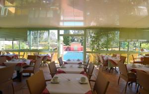 a restaurant with tables and chairs and a pool at Hotel Cyrnea in Calvi