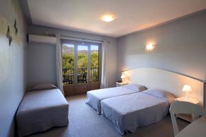 a bedroom with two beds and a balcony at Hotel Cyrnea in Calvi
