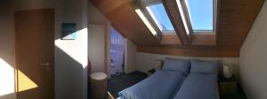 Schlafzimmer mit einem Bett mit blauer Bettwäsche und einem Fenster in der Unterkunft Hotel BZ Sunnahof in Oberschan