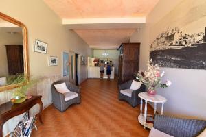 a hallway with two chairs and a table and a painting at Hotel Cyrnea in Calvi